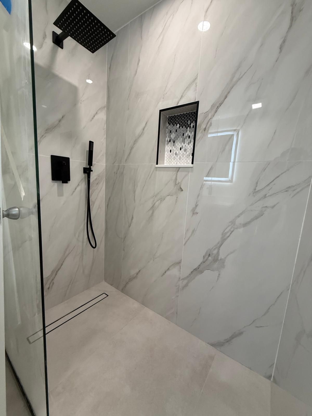 Curbless shower with large-format marble-look tile and a recessed niche