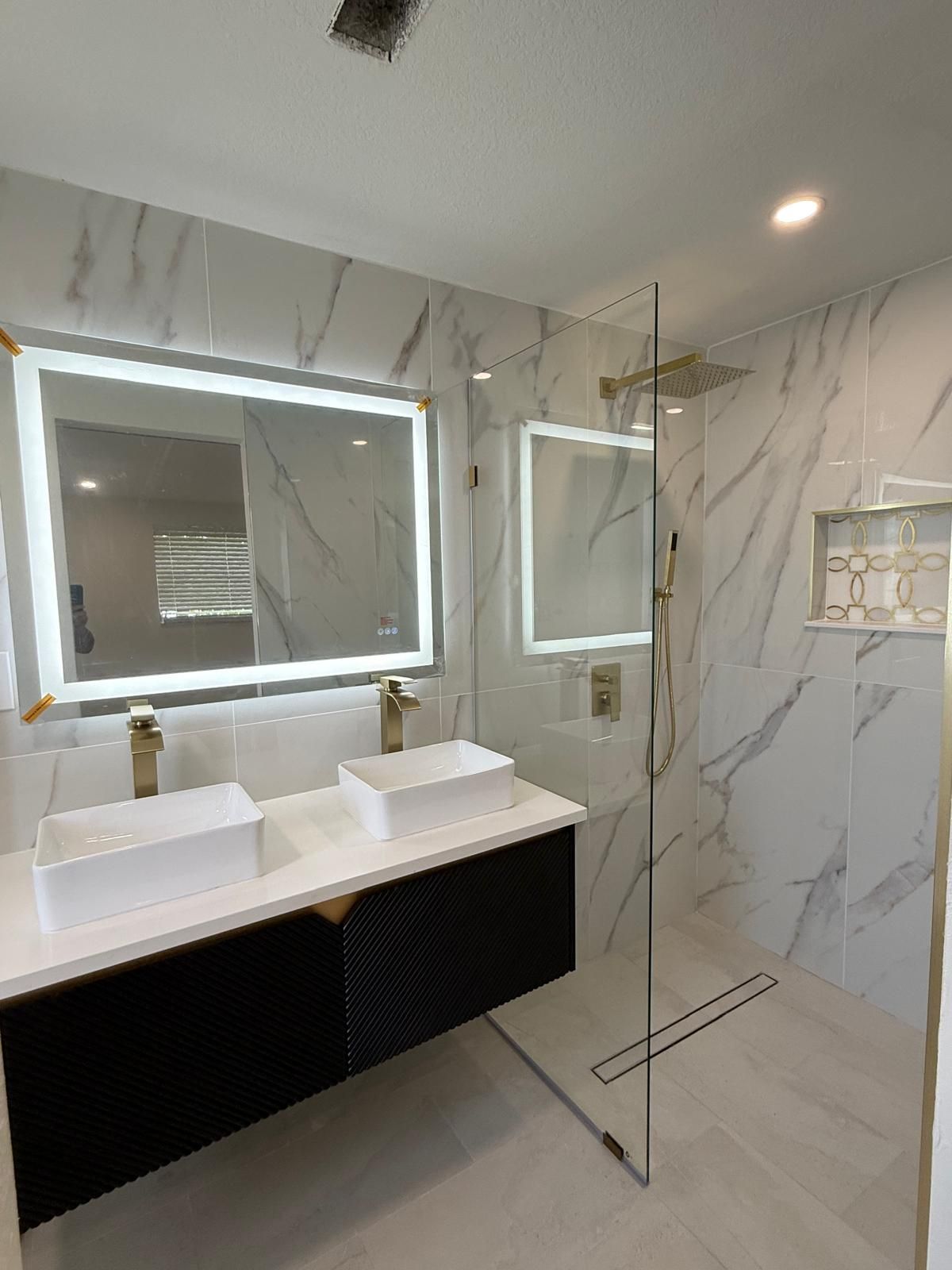 Marble-look tile bathroom with glass shower panel and double vanity