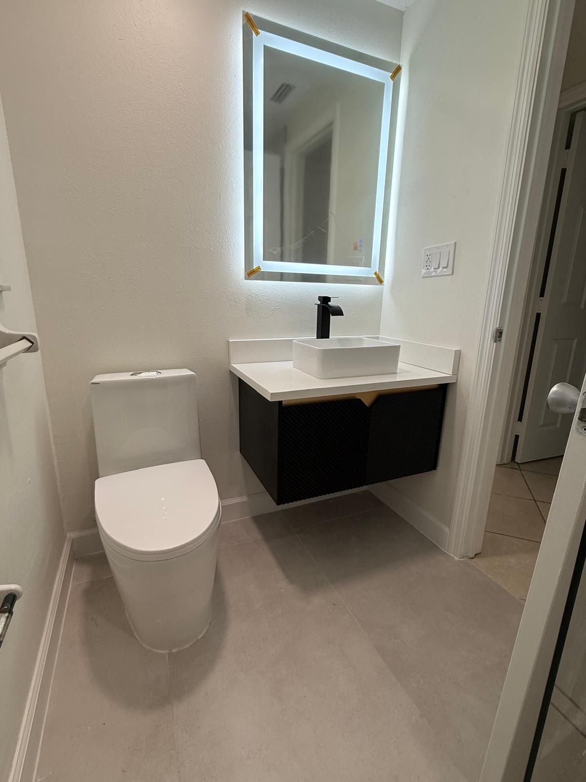 Powder room with a floating vanity, vessel sink and backlit mirror