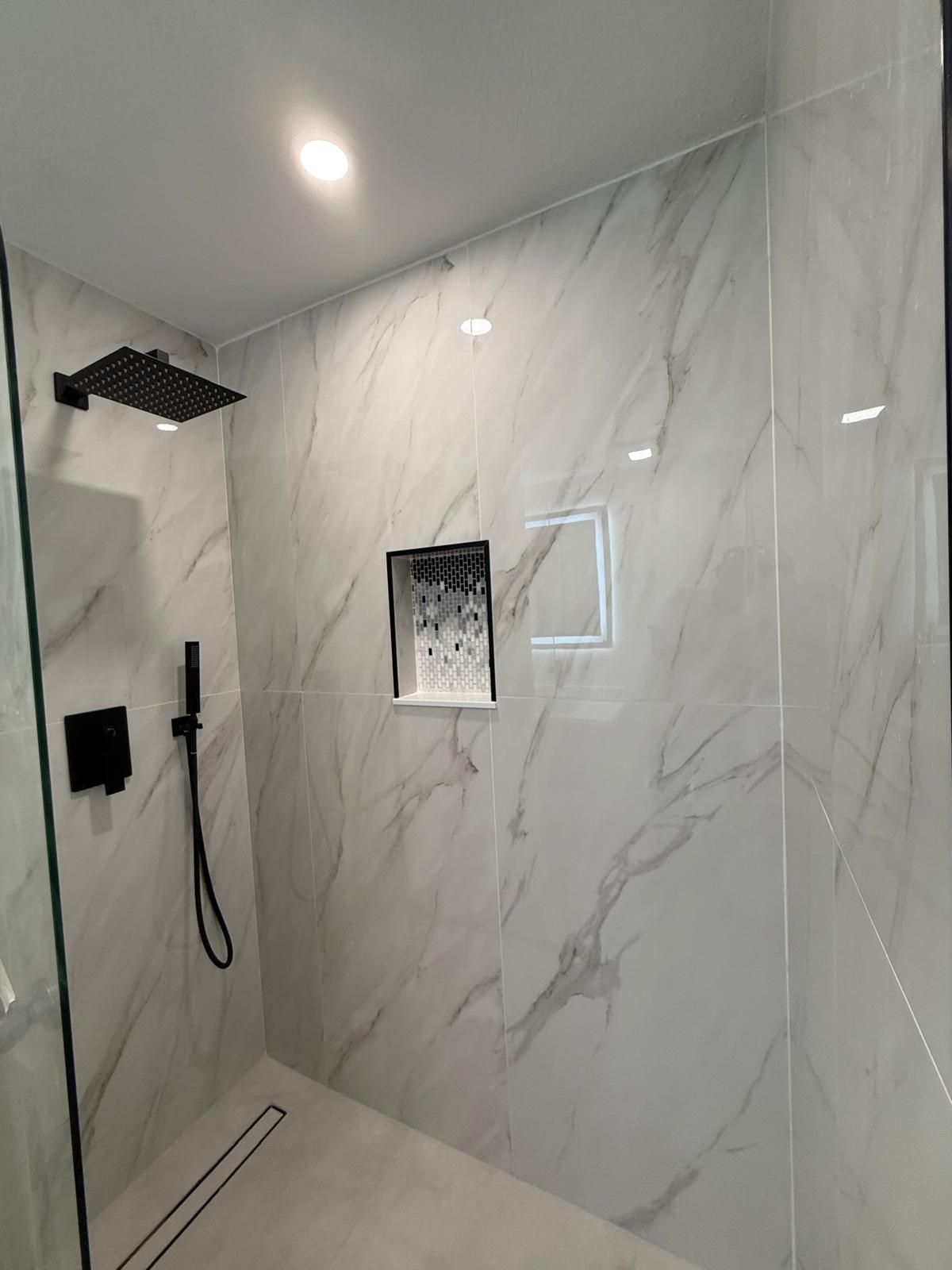 Walk-in shower with matte black rain shower head and linear drain